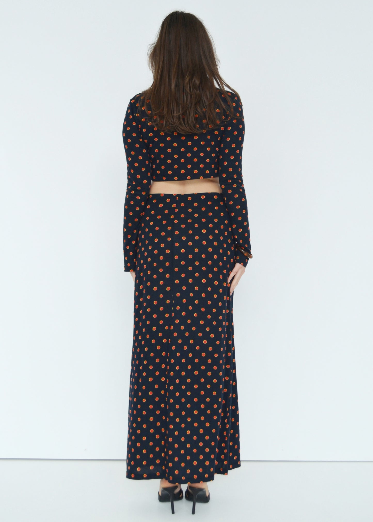 Woman facing back wearing the Isabel maxi skirt low rise and matching Tati flared long sleeve cropped top in navy Japanese Tashi Spot print against white wall. Australian made. 
