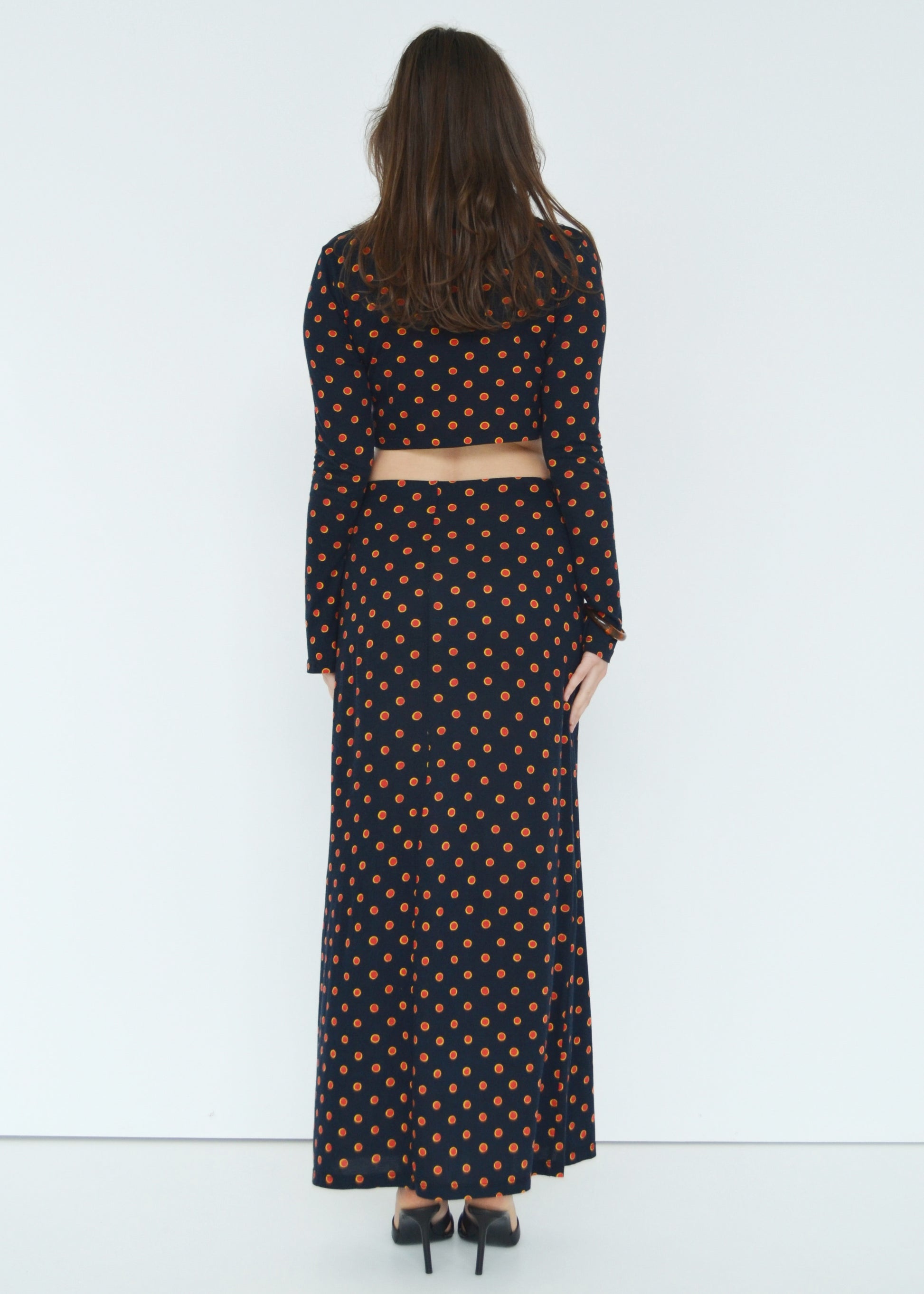 Woman facing back wearing the Isabel maxi skirt low rise and matching Tati flared long sleeve cropped top in navy Japanese Tashi Spot print against white wall. Australian made. 