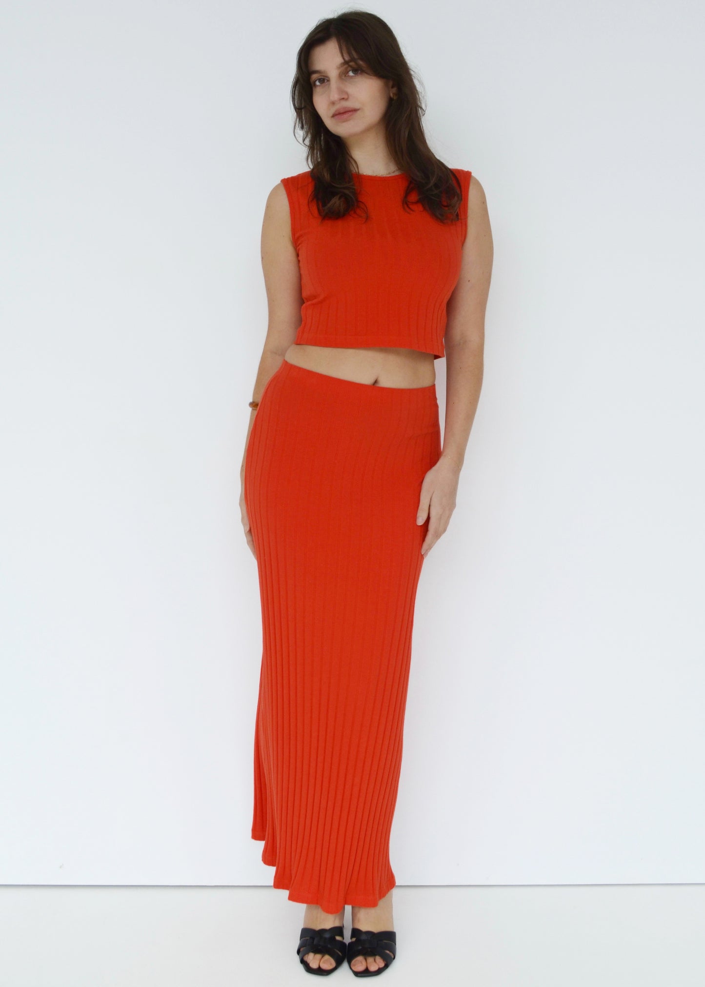 Woman wearing a red ribbed top and skirt set against a white background front side