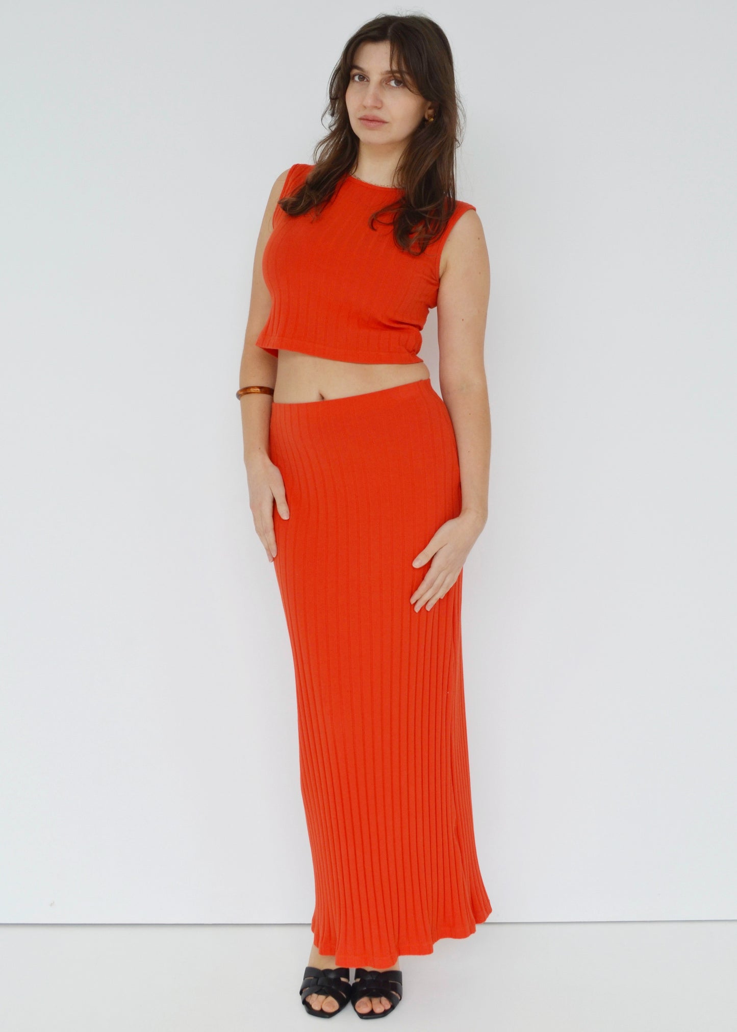 Woman wearing a bright orange outfit against a white background