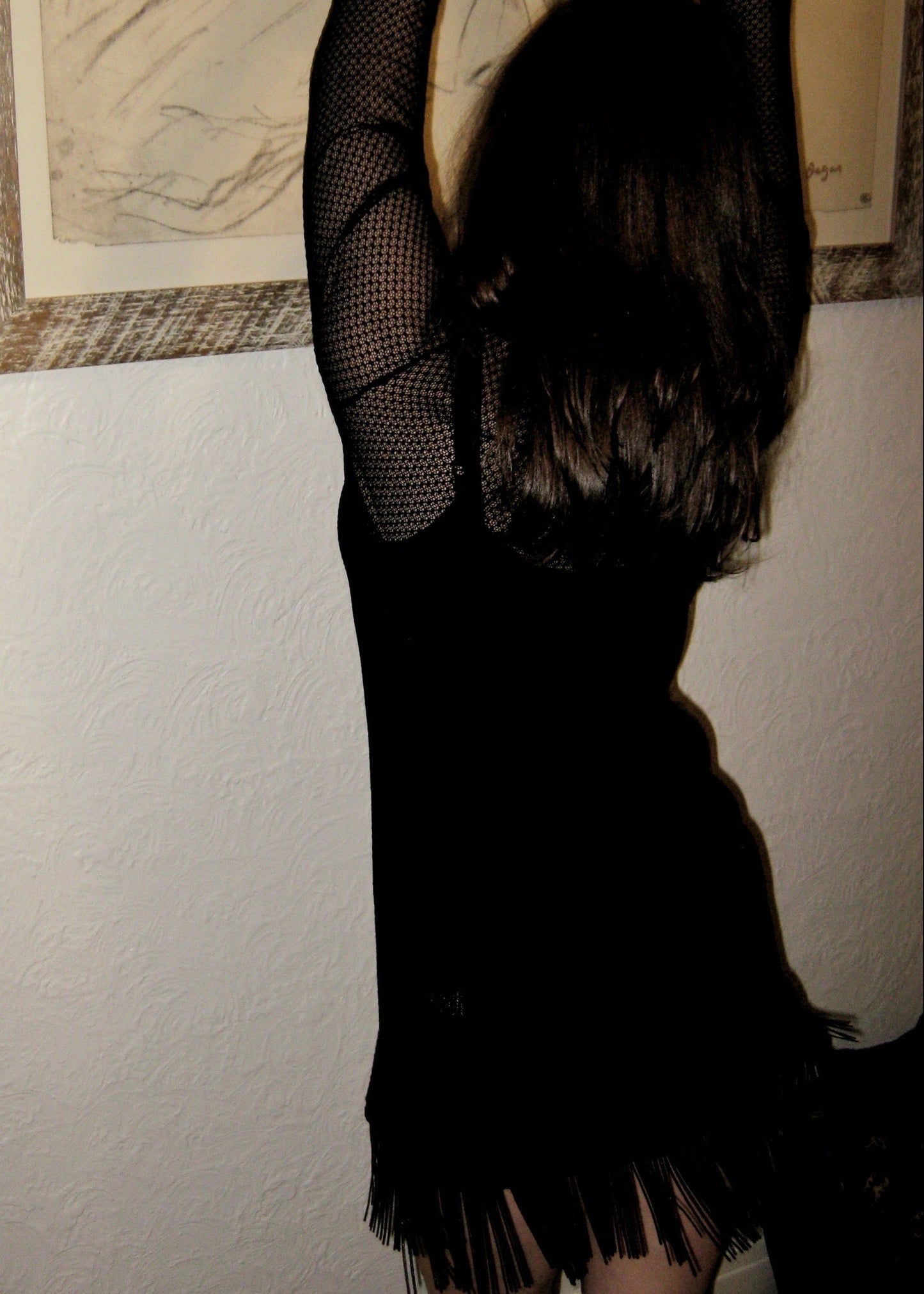 Woman wearing the Kea dress with fringe edge in black Italian micro floral lace facing the wall showing fringe movement. Made in Australia.