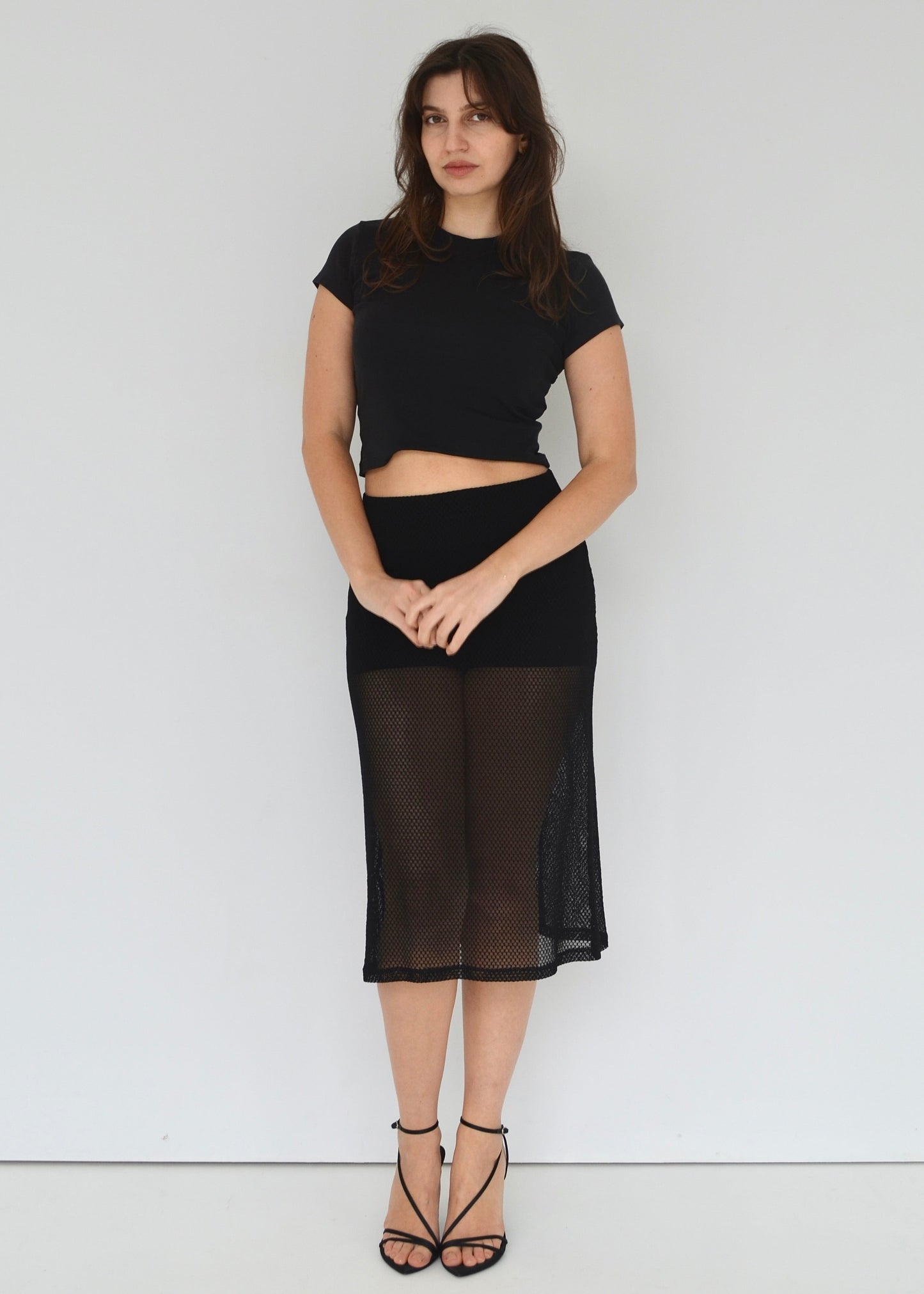 Woman wearing a black outfit with a sheer skirt against a white background