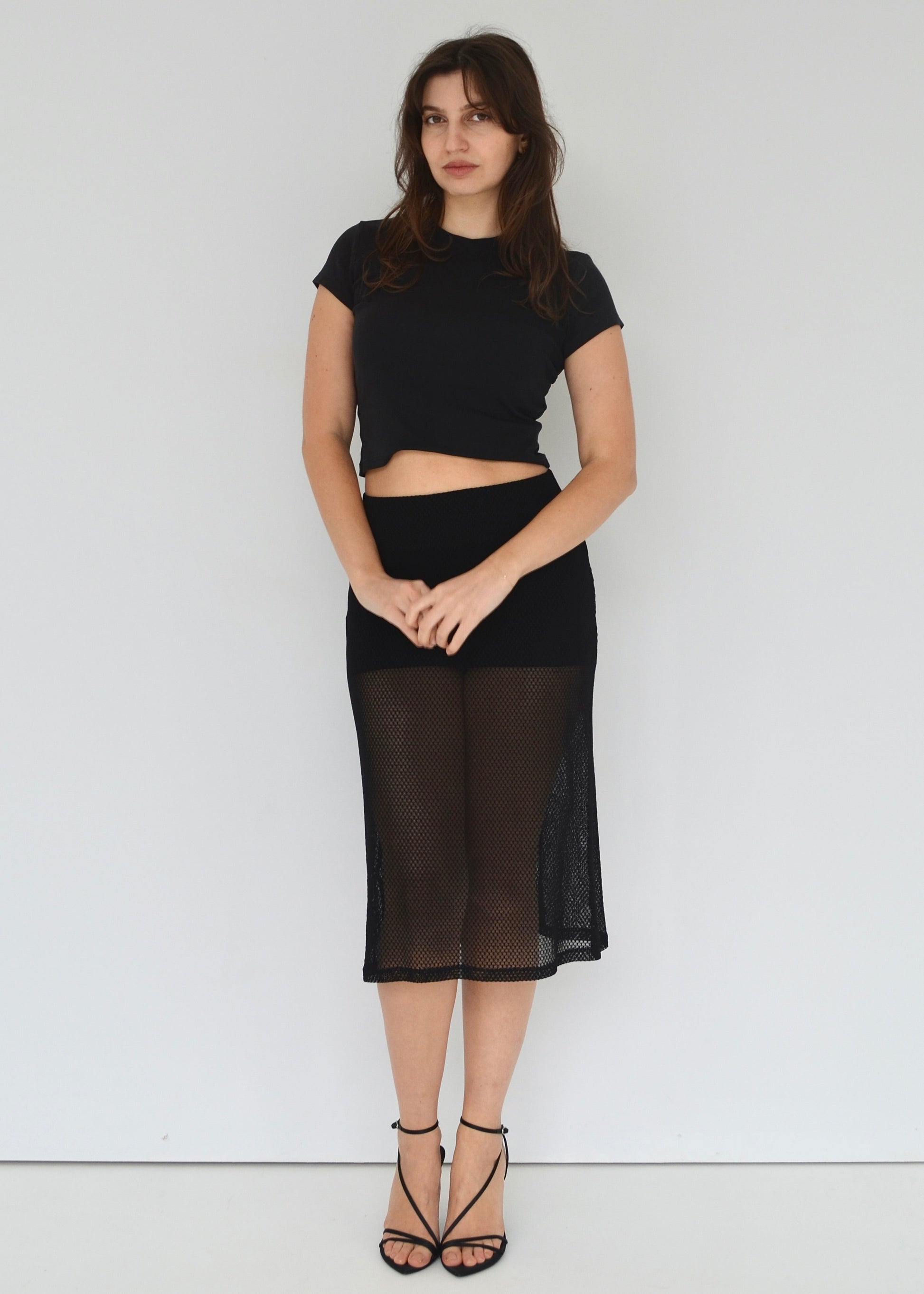 Woman wearing a black outfit with a sheer skirt against a white background