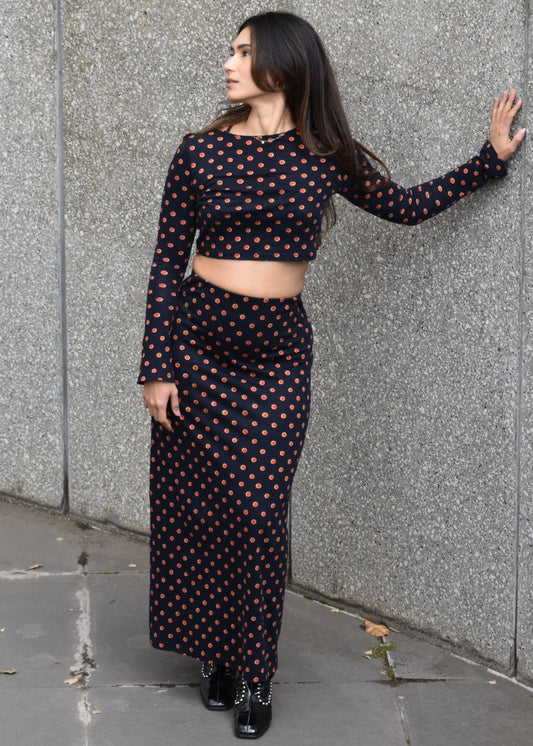 Woman in a Missou polka dot spot long sleeve crop top and maxi skirt standing on a gray pavement

