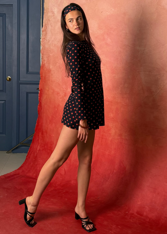 Woman taking a photo of another woman  in Missou spot dress in front of a red backdrop

