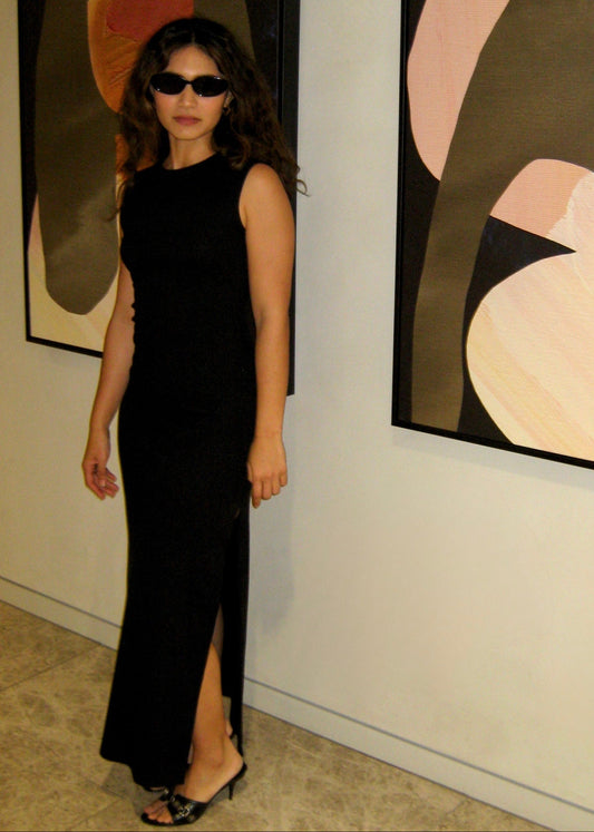 Woman in a black japanese dress standing in front of abstract art in an art gallery.

