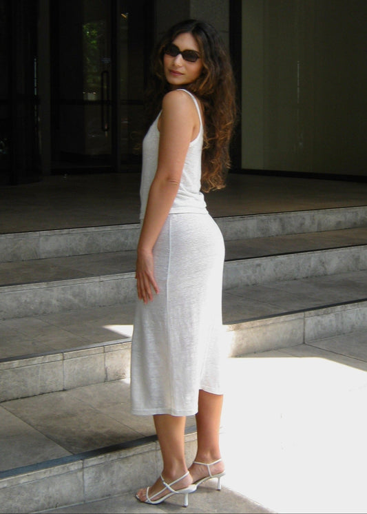 Woman in a white Japanese linen cami top and midi skirt standing on steps outside a modern building


