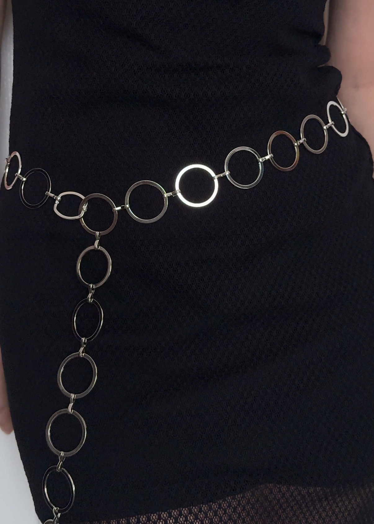 A Missou silver metal chain belt with interlocking circular links, worn at the waist over a black Italian lace dress.